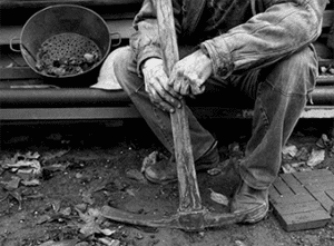 Coal miner sitting with pick axe