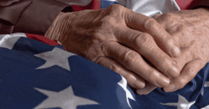 Old hands rest on an American flag
