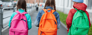 three children with backpacks walking