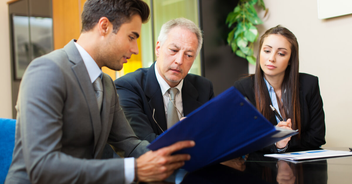 Three people in business clothing review paperwork