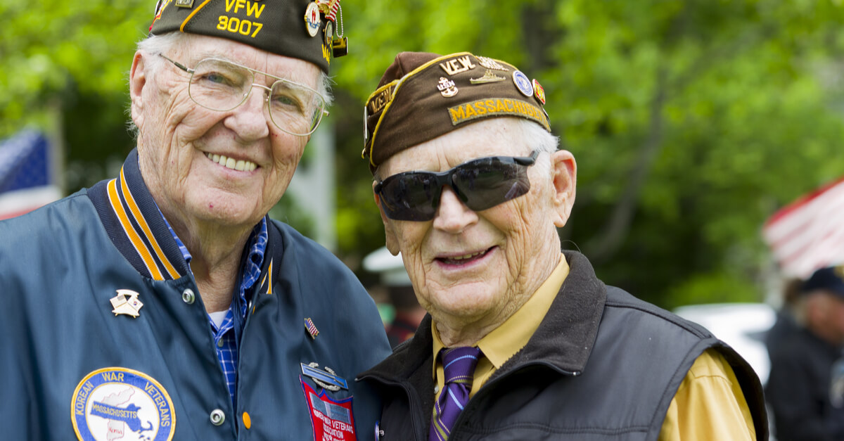 Two older veterans stand next to one another