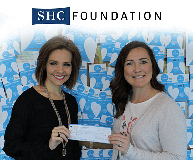 Two women hold up a check.