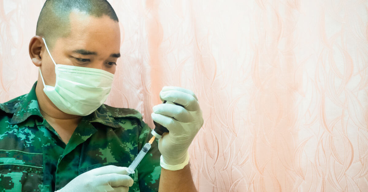 a doctor in a military uniform holds up a syringe