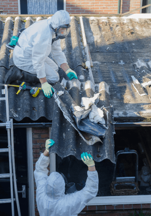 Two workers in white hazmat suits work on a roof to remove asbestos shingles