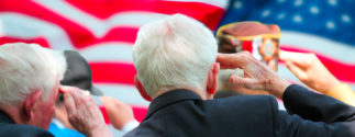 a group of older veterans salute the American flag