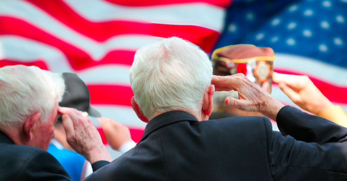 a group of older veterans salute the American flag