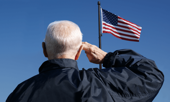 An older man salutes the American flag