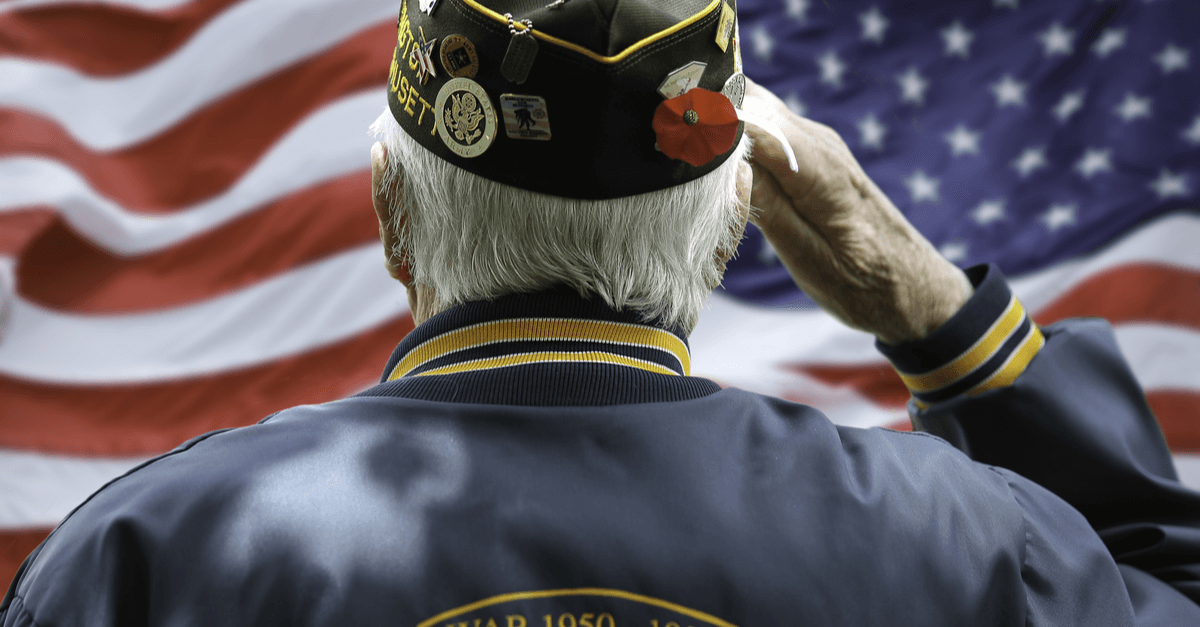 an older U.S. veteran in uniform salutes the American flag