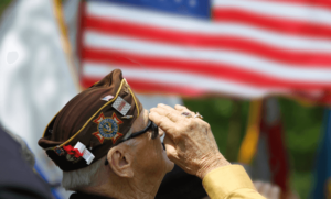 An older veteran salutes an American flag