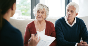 an older couple sits with a younger person who is holding documents in their hand.