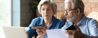 an older couple looks at documents and a computer screen