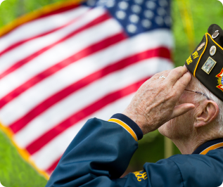 A U.S. veteran stands outside and salutes and American flag