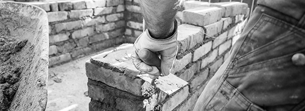 close up of a masons hands laying brick