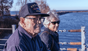 A veteran sitting next to a woman on a pier