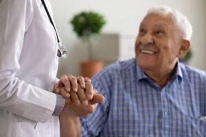 An older man holds a doctor's hand