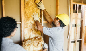 A man installing insulation in a wall