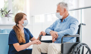 Senior man in wheelchair talking to nurse