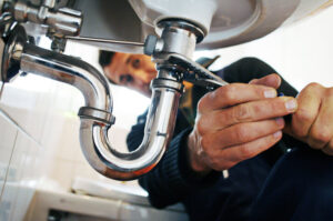 a plumber tightens a pipe underneath a sink