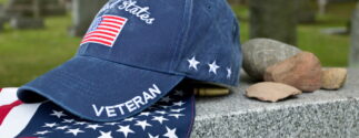 Veteran hat and flag resting on headstone