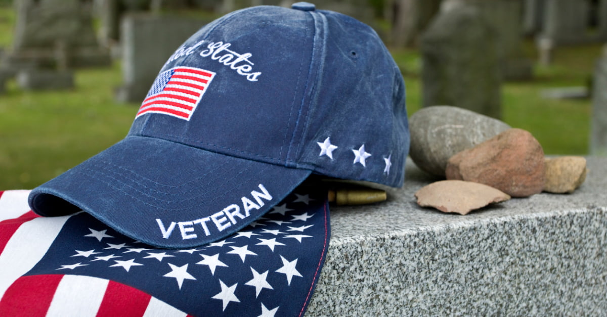 Veteran hat and flag resting on headstone