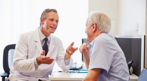 A male doctor meets with an older male patient.
