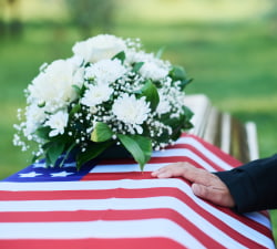 Closeup of a casket with an American flag and flowers sitting on it