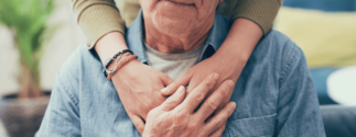 A younger person wraps their hands around an older person