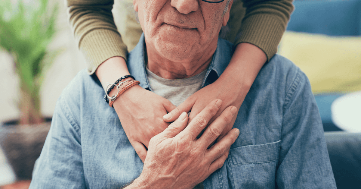 A younger person wraps their hands around an older person