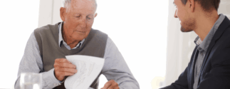 An older man meets with a mesothelioma lawyer to review paperwork