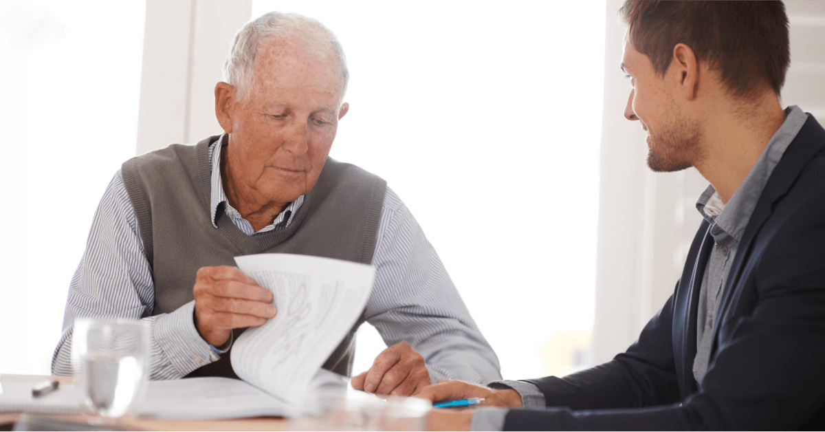 An older man meets with a mesothelioma lawyer to review paperwork