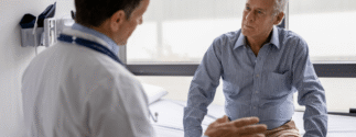 An older man sits with a younger male doctor